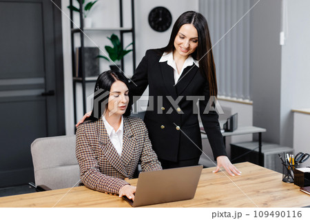 Call center agent with headset working on support hotline in modern office. Two young attractive women are working in the office 109490116