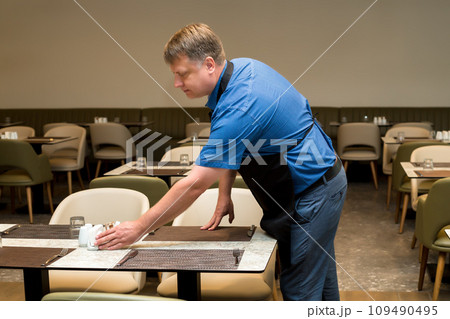 A man clears a table in a cafe at the end of the working day 109490495