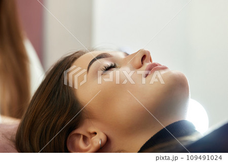 cosmetologist using primer spray for eyelash extension procedure in salon 109491024