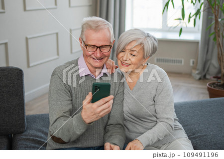 Video call. Happy senior couple woman man with smartphone having video call. Mature old grandmother grandfather talking speaking online. Older generation modern tech usage. Virtual meeting online chat 109491196