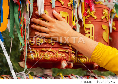 Person pilgrim female hand touching turning spinning Buddhist prayer wheel at Buddhist monastery. Prayer wheels in Buddhist stupa temple. Buddhism religion concept 109491253