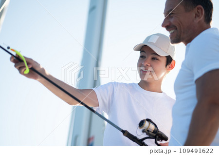 Teen and his dad on a yacht with a fishing rod Teen and his dad on a yacht with a fishing rod 109491622