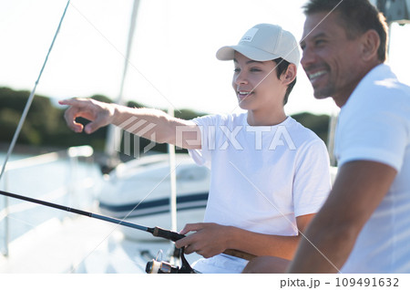Teen and his dad on a yacht with a fishing rodの写真素材 [109491632] - PIXTA