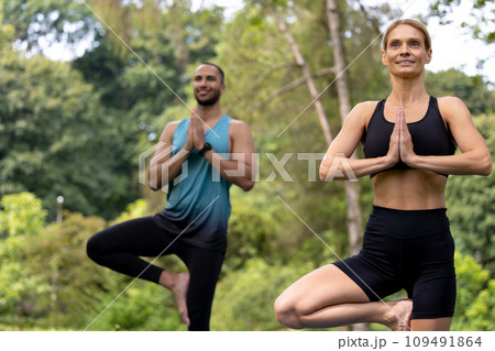 Man and woman doing yoga exercises in green park. 109491864