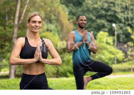 Man and woman doing yoga exercises in green park. 109491865