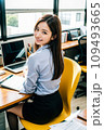 デスクで仕事をしながらこちらを向いて微笑む女性/AI画像 109493665