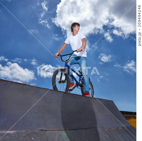 Riding, bike and teen on ramp for sport performance or event at park in summer with blue sky mockup. Bicycle, stunt or kid balance on edge of board for trick in cycling competition or challenge 109494246