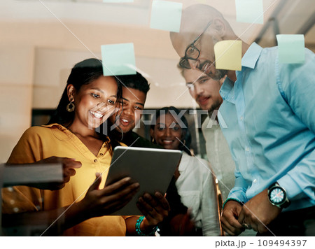 Group of creative, excited and smiling design team, working, researching and browsing on tablet for innovation ideas in modern office. Office workers planning a group work project after hours. 109494397