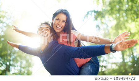 Outdoor, piggy back and couple with love, nature and summer with lens flare, marriage and adventure. Portrait, man carrying woman and woods for fun, playing and journey with relationship and romance 109494772