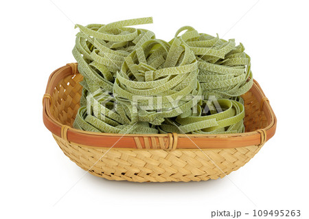 Raw tagliatelle green pasta with spinach in a wicker basket isolated on white background Raw tagliatelle green pasta with spinach in a wicker basket isolated on white background 109495263