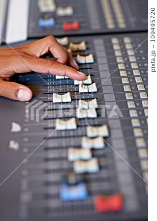 Hand, mixing and sound board in recording studio with dj, technology and media on desk. Music, deck and person editing with equipment for audio, production and moving switch on console for radio song 109495720