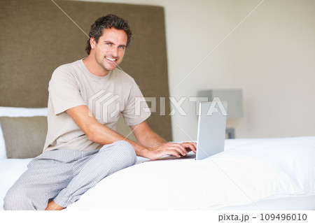 Portrait, man in bedroom and laptop to work from home, typing and sitting in bed for freelance job. Technology, Entrepreneur and remote worker for online job, company and marketing projects 109496010