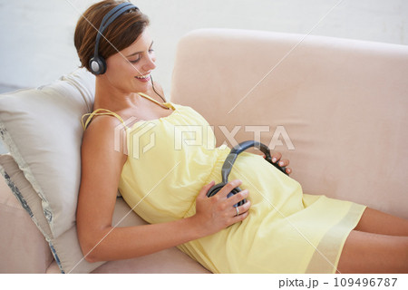 Woman, music or headphones on pregnant stomach in home living room for sound, audio or listening development for baby. Relax, pregnancy or person with podcast for childcare wellness or growth support 109496787