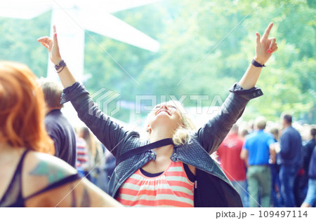 Woman, dancing and happy outdoor at music festival for freedom, performance and entertainment with crowd. Person, cheering and smile at event, concert or show with audience in nature for summer party 109497114
