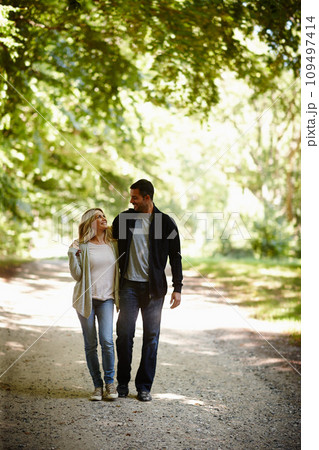 Always by each others side. Full length shot of a young couple walking arm in arm in a park. Always by each others side. Full length shot of a young couple walking arm in arm in a park. 109497414