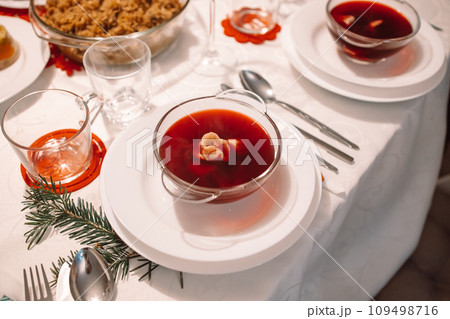 Christmas beetroot soup, borscht with small dumplings with mushroom filling in a ceramic bowl on a table. Traditional Christmas eve dish in Poland.  109498716