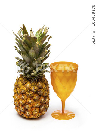 Ripe pineapple with a cup on a white background 109499279
