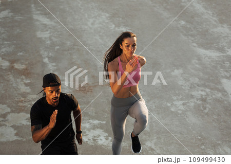 High angle of two athletes running together on the roof at sunset High angle of two athletes running together on the roof at sunset 109499430