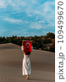 A beautiful dark-haired woman holds a Turkish flag in her hands, rear view. A woman is traveling in Turkey. A tourist on the background of Patara beach in Turkey. Vacation in Turkey. Turkish flag 109499670
