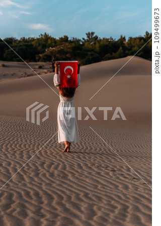A beautiful dark-haired woman holds a Turkish flag in her hands, rear view. A woman is traveling in Turkey. A tourist on the background of Patara beach in Turkey. Vacation in Turkey. Turkish flag A beautiful dark-haired woman holds a Turkish flag in her hands, rear view. A woman is traveling in Turkey. A tourist on the background of Patara beach in Turkey. Vacation in Turkey. Turkish flag 109499673