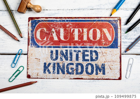 United Kingdom. Metal CAOTION plate with text on a white wooden background United Kingdom. Metal CAOTION plate with text on a white wooden background 109499875