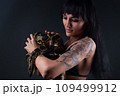 Photo of brunette woman holding yellow anaconda in shadows 109499912