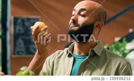 Shop owner gives lemons to client to smell and enjoy aromatic fresh citrus scent, man buying locally grown produce to support local sustainable business and storekeeper. Handheld shot. Shop owner gives lemons to client to smell and enjoy aromatic fresh citrus scent, man buying locally grown produce to support local sustainable business and storekeeper. Handheld shot. 109500212