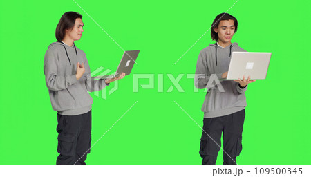 Person waving at online videocall on pc, meeting with people on internet connection teleconference. Asian adult holding laptop and discussing with friends on conference call, greenscreen. 109500345