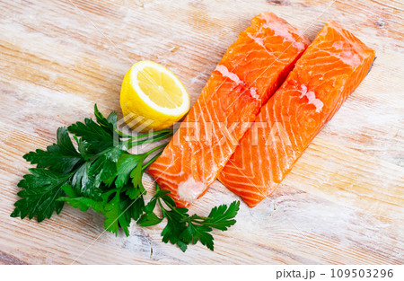 Raw salmon fillet with lemon and greens before cooking Raw salmon fillet with lemon and greens before cooking 109503296