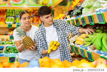 Young husband and wife choose fresh fruit together in grocery supermarket 109503534