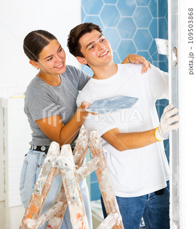 Young couple laying ceramic tiles on walls during home renovation 109503868