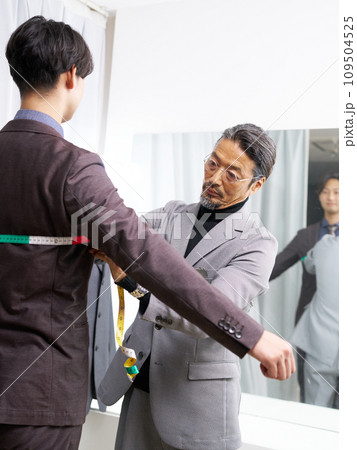 鏡の前で顧客の採寸をするテーラーのスタッフ 109504525