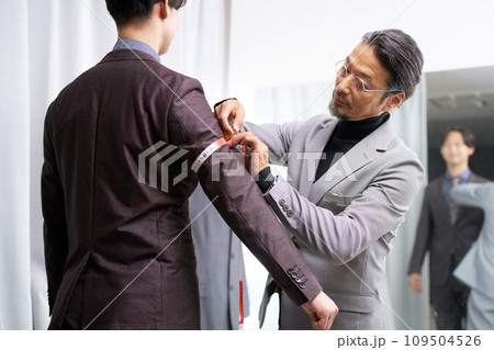 鏡の前で顧客の採寸をするテーラーのスタッフ 鏡の前で顧客の採寸をするテーラーのスタッフ 109504526