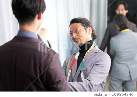 スーツのフィッティングをするスタイリスト 109504540