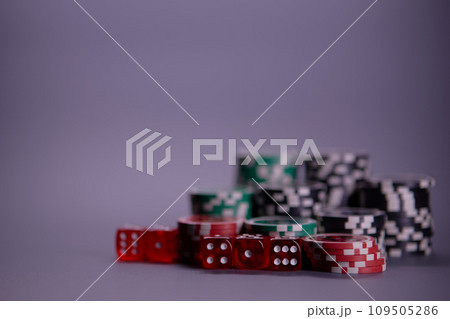 Casino games and gambling concept with stacked poker chips and red dice used in the game of craps. Copy space. Casino games and gambling concept with stacked poker chips and red dice used in the game of craps. Copy space. 109505286