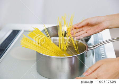 キッチンでスパゲッティを調理する女性 109507809