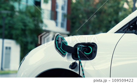 Electric car plugged in with home charging station. Peruse 109509422