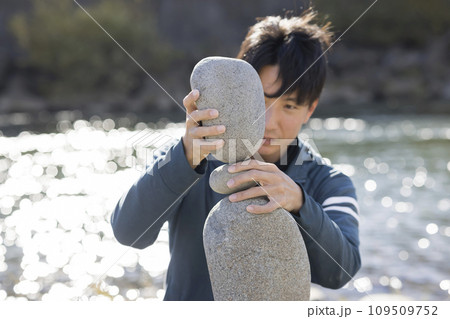 風の強い中ロックバランシングに挑戦する男性 109509752