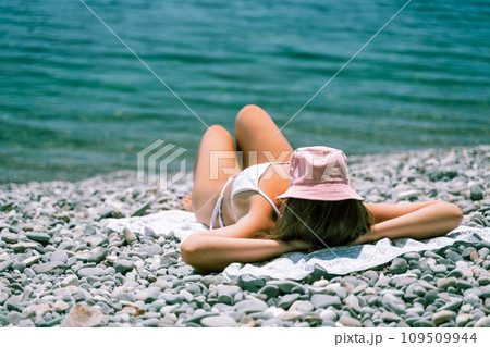 Woman white bikini beach tan. Happy woman in swimwear and hat on vacation. Summer travel holidays vacation on the sea Woman white bikini beach tan. Happy woman in swimwear and hat on vacation. Summer travel holidays vacation on the sea 109509944
