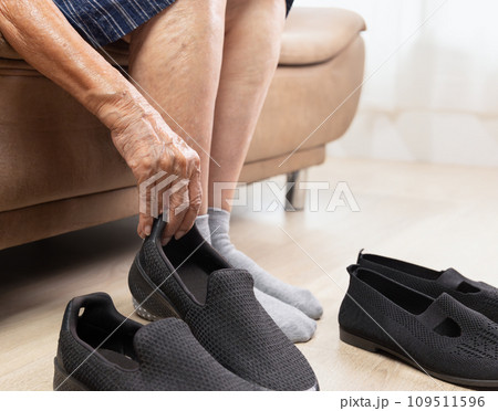 Elderly woman put on and take off shoes at home 109511596