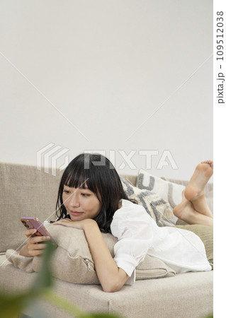 自宅でリラックスしてスマホを操作する女性 自宅でリラックスしてスマホを操作する女性 109512038
