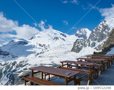 Saas-Fee, Switzerland - June 16th 2023: View from the terrace of Britanniahuette towards wide glaciers and peaks Saas-Fee, Switzerland - June 16th 2023: View from the terrace of Britanniahuette towards wide glaciers and peaks 109512206