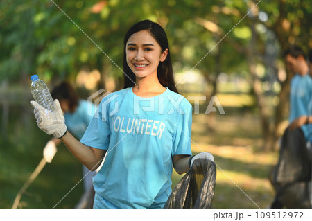 Beautiful female volunteer with garbage bag cleaning up the forest. Charity and ecology concept 109512972