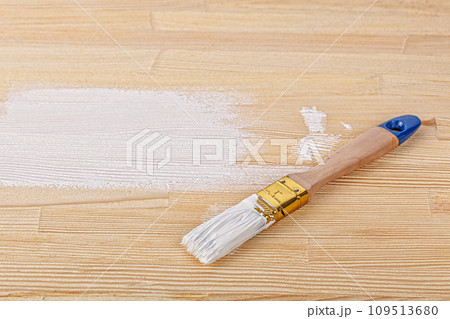 white paint with a brush on a wooden background with texture 109513680