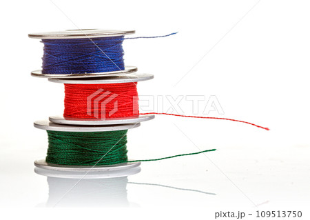 spools of thread in blue, red, green colors on a white background 109513750