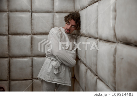 Calm man with schizophrenia mental disorder in white padded room 109514483