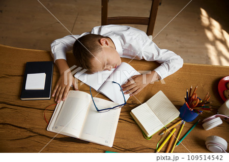 Overhead view on exhausted little schoolboy sleeping on desk table Overhead view on exhausted little schoolboy sleeping on desk table 109514542