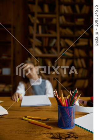 Tired schoolgirl studying at home, selective focus on stationery glass Tired schoolgirl studying at home, selective focus on stationery glass 109514555