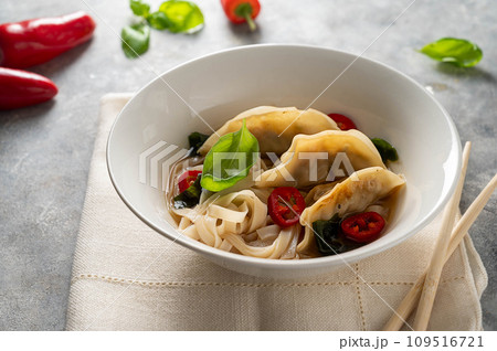 Spicy miso soup with dumplings and rice noodles in white bowl Spicy miso soup with dumplings and rice noodles in white bowl 109516721