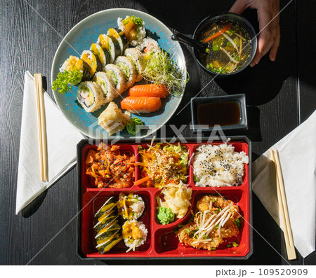 Japanese Lunch in Bento Box with Deep-Fried Squid Rings, Sushi Rolls, Salad, Rice, Pickled Ginger Japanese Lunch in Bento Box with Deep-Fried Squid Rings, Sushi Rolls, Salad, Rice, Pickled Ginger 109520909